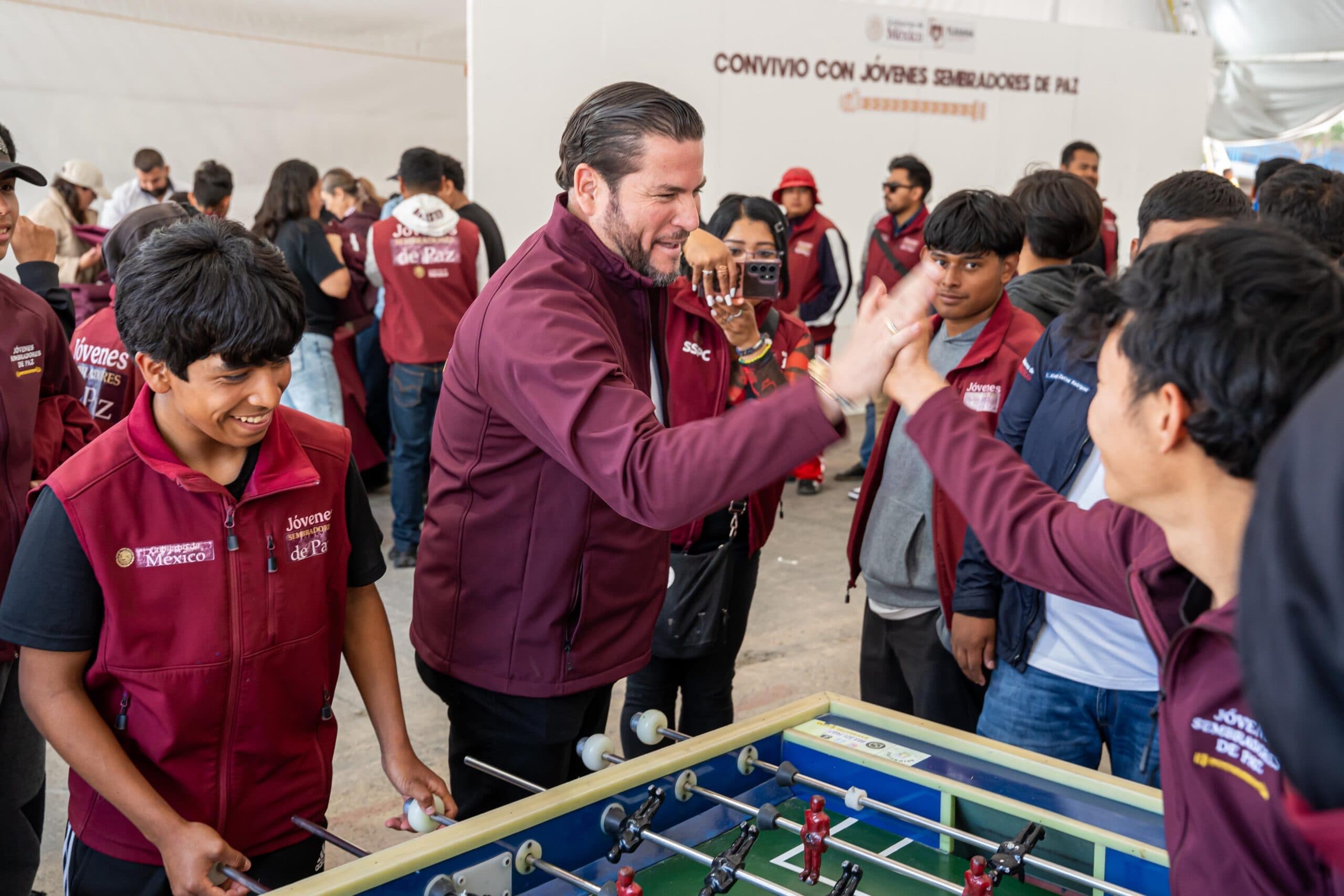 Ismael Burgueño interactúa con jóvenes sembradores de paz durante un evento, jugando al futbolito y compartiendo momentos de camaradería.