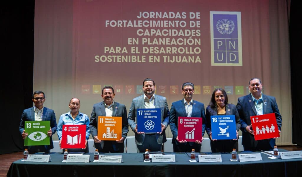 Ismael Burgueño y funcionarios sostienen carteles con los ODS en las Jornadas de Fortalecimiento para la Agenda 2030 en Tijuana.