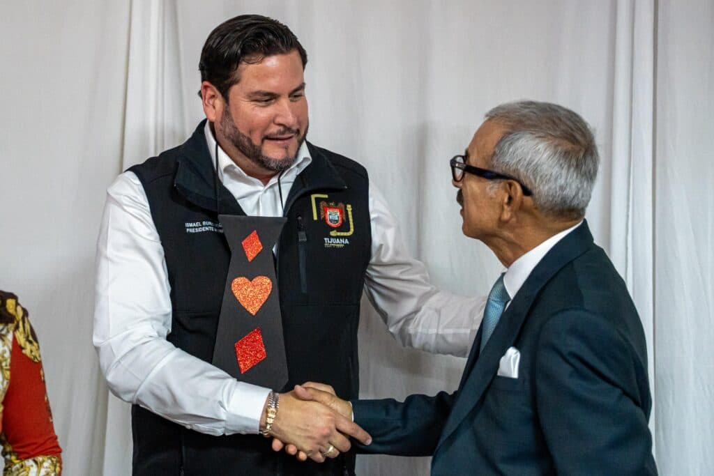 Ismael Burgueño Ruiz estrecha la mano de un docente jubilado durante la celebración del Día del Maestro en Tijuana.