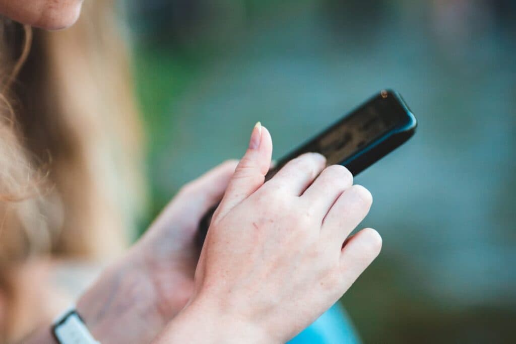 Persona usando un teléfono móvil para verificar información, en el contexto de la prevención de desinformación durante eventos masivos.