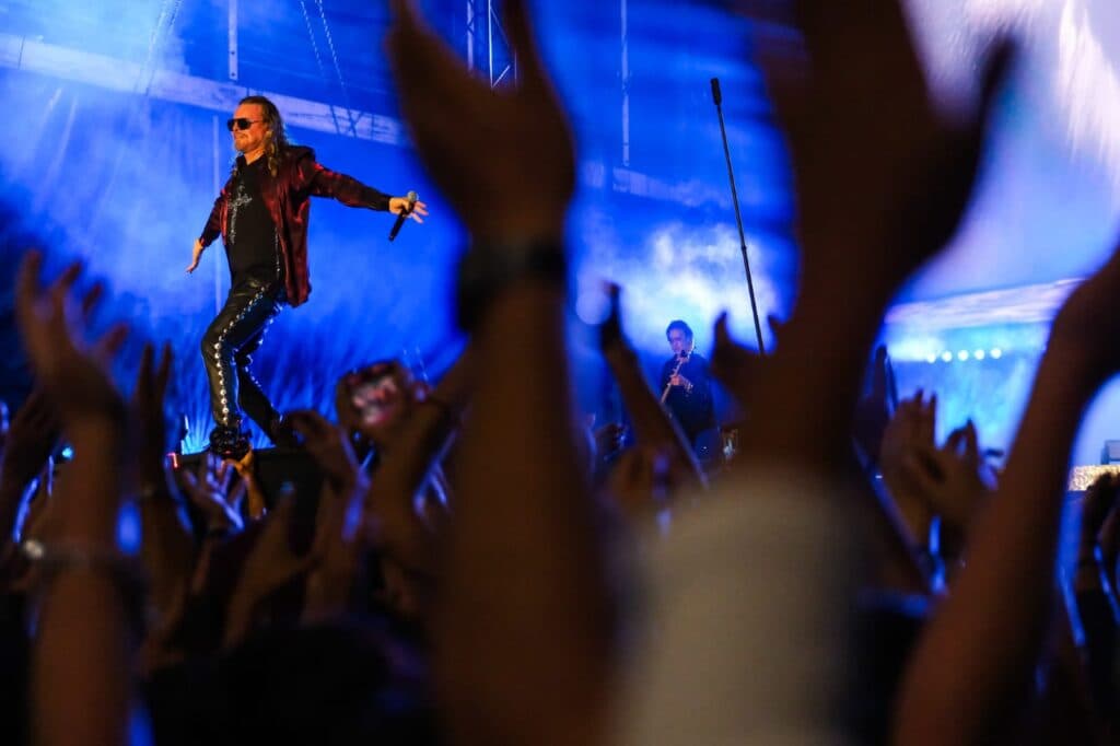 Vocalista de Maná enérgicamente interactuando con el público durante el concierto en La Minerva, Guadalajara, con luces y manos levantadas.