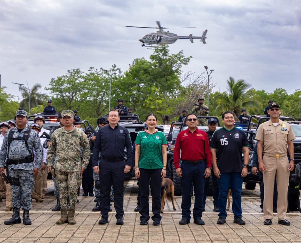 Estefanía Mercado junto a autoridades y elementos de seguridad, con un helicóptero sobrevolando durante el inicio del