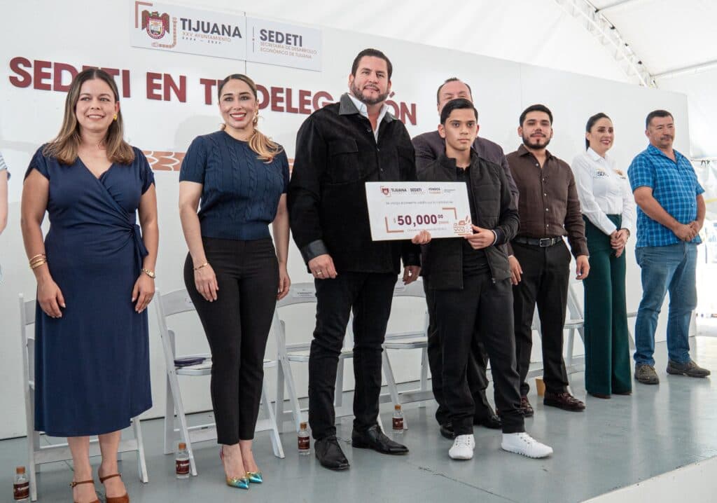 Ismael Burgueño entrega un cheque simbólico a un joven emprendedor durante el evento ‘SEDETI en tu Delegación’ en Tijuana.