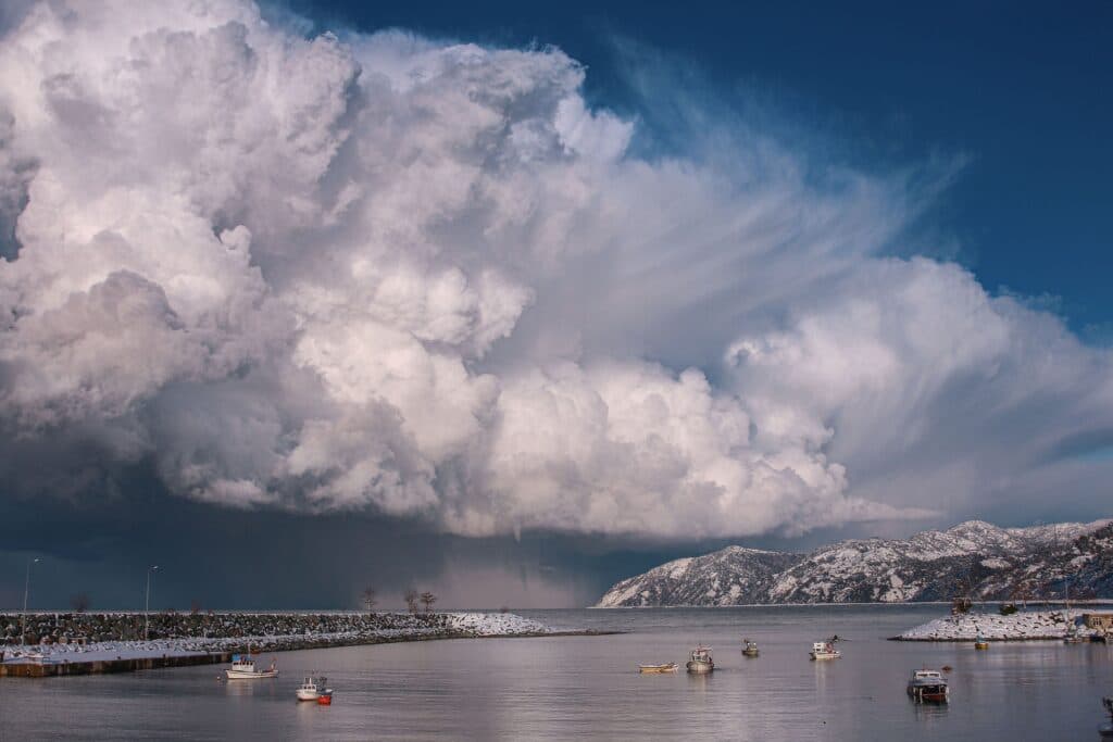 Nubes densas y amenazantes sobre un puerto con barcos, reflejando condiciones climáticas inusuales relacionadas con El Niño.