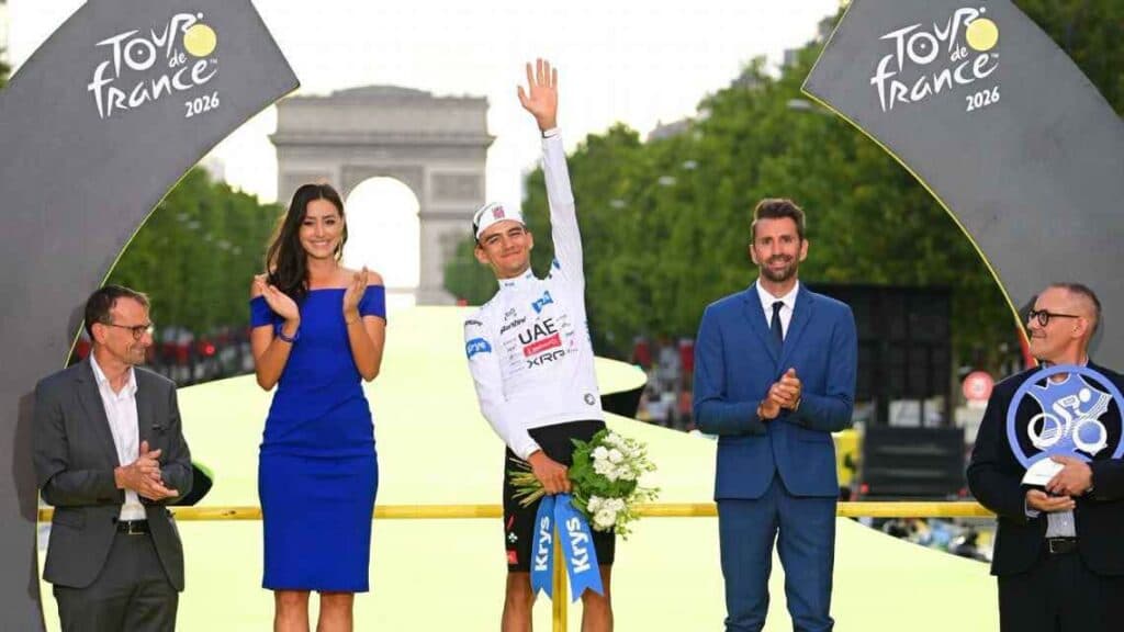 Isaac del Toro en el podio del Tour de Francia 2026, celebrando su tercer lugar junto a presentadores y el Arco del Triunfo al fondo.