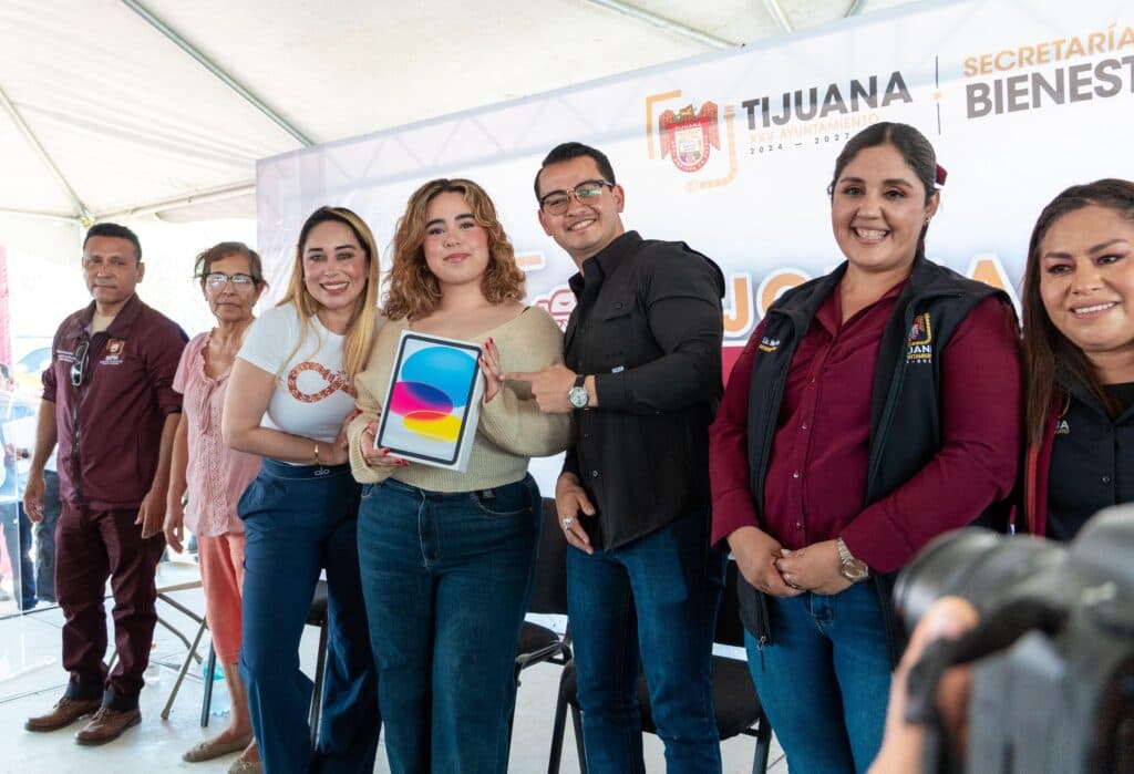 Abdiel Gutiérrez Coronado y Teresita Balderas entregan un tablet a una joven durante la Macro Jornada del Pueblo en Tijuana.