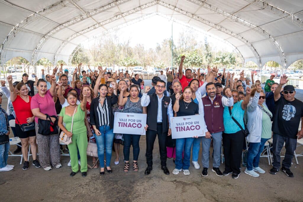 Alcalde Abdiel Gutiérrez junto a familias de La Presa Abelardo L. Rodríguez, levantando carteles de "Vale por un tinaco" en evento de entrega.