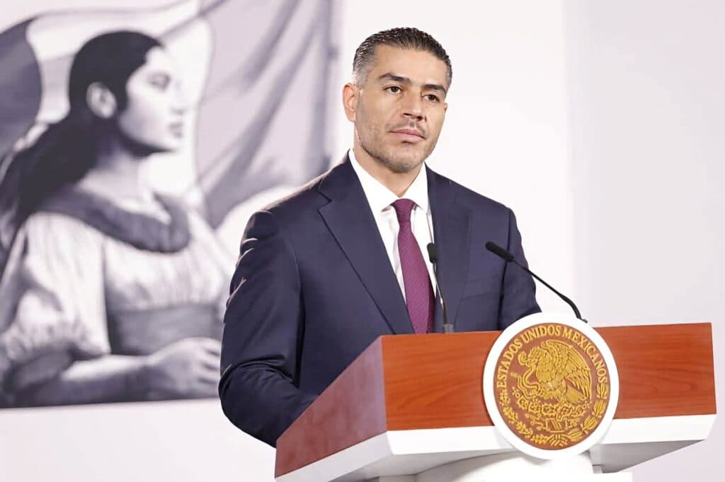 Omar García Harfuch, secretario de Seguridad, durante una conferencia sobre la percepción de inseguridad en México, con un mural de fondo.