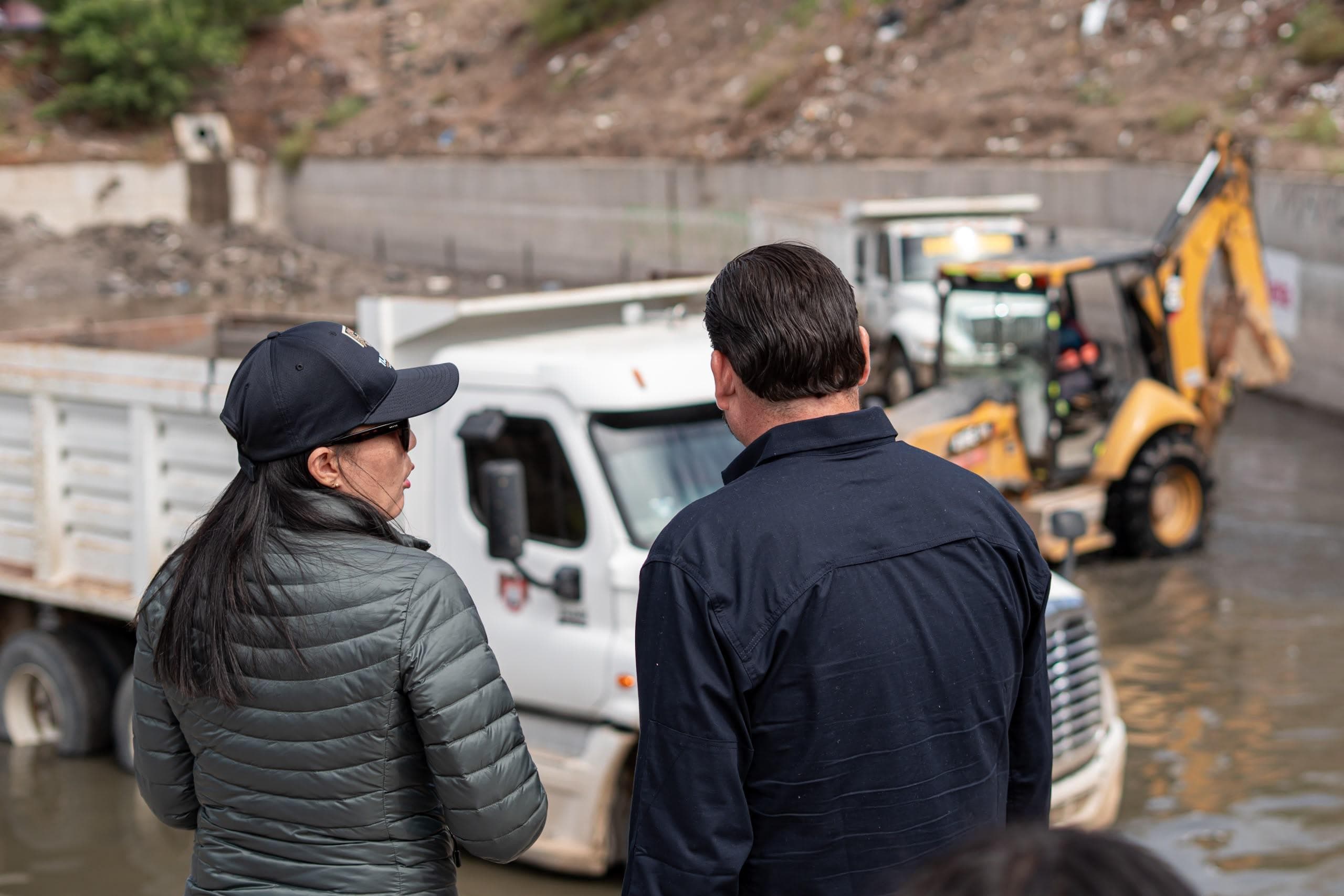 Ismael Burgueño Ruiz supervisa trabajos de limpieza en el desarenador Florido 1, junto a una colaboradora, mientras maquinaria opera en el fondo.