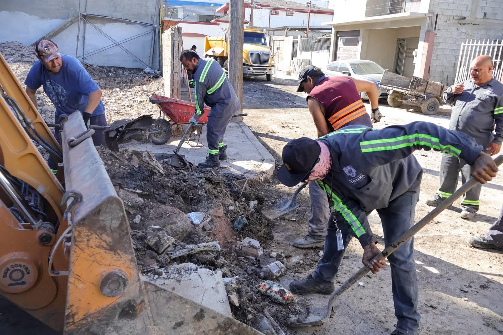 Trabajadores del XXV Ayuntamiento de Tijuana realizan labores de limpieza y desazolve en una calle, tras las lluvias recientes.